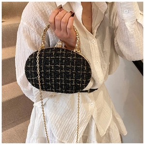 Detail of black and gold tweed clutch bag with intricate gold handle and diamond clasp