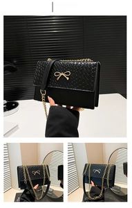 Detail of black crocodile texture bag with woven flap and golden bow metal clasp