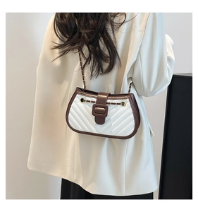 Détail du sac à main matelassé blanc avec bordure marron et bandoulière dorée