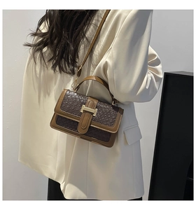 Detail view of dark brown crocodile embossed shoulder bag with gold metal buckle hardware