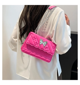 Close-up of bright pink quilted crossbody bag with silver butterfly and chain strap