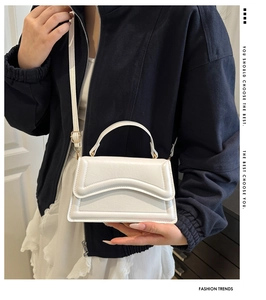 Détail d'un sac bandoulière blanc en simili cuir avec rabat ondulé et sangle réglable