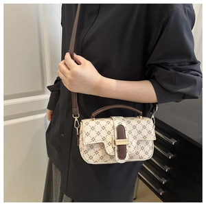 Detail of beige crossbody bag with cross pattern, brown handle and metal buckle