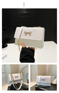 Detail of white stone-pattern handbag featuring a gold bow accent and woven texture