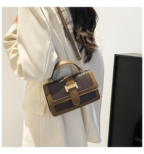 Detail of cross-woven texture and gold buckle on a retro brown straw small square bag