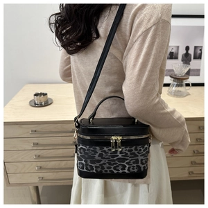 Detail of leopard print bucket bag with gold zippers and adjustable strap in cozy setting