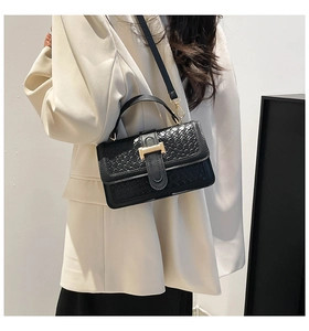 Close-up of black woven texture bag with a luxury golden H-shaped metal clasp detail