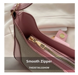 Detailed close-up of smooth gold zipper on pink and beige patchwork saddle bag