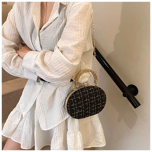 Detail of black tweed evening bag with gold chain strap and crystal clasp on model