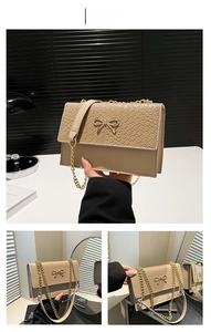 Detail view of khaki handbag featuring woven texture flap and golden bow ornament