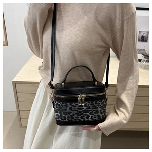 Detail of crossbody bag featuring black smooth leather and leopard print patchwork texture