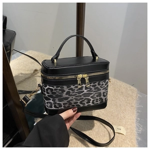 Detail view of stylish leopard print crossbody bag with golden dual zippers and black handle