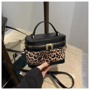 Detail of leopard print crossbody bag with golden dual zippers and leather handle