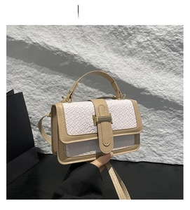 Detail of white woven straw crossbody bag with beige leather trim and gold hardware