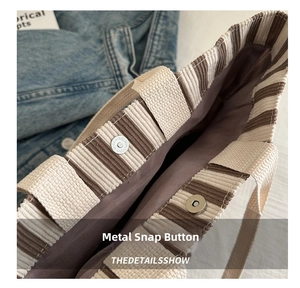 Close-up of magnetic hardware buckle on striped corduroy tote bag with durable lining