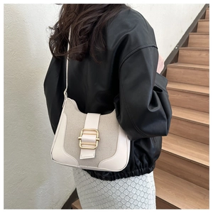 Detail of hobo shoulder bag featuring cream fabric and leather texture with gold buckle