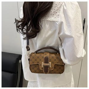 Detail of vintage geometric patterned crossbody bag showing leather straps and gold buckle