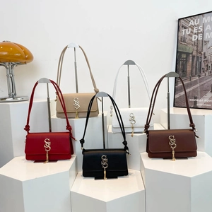 Retro crossbody bag with metal logo and tassel charm in five classic colors on a pedestal