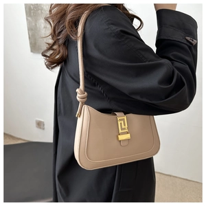 Dettaglio borsa a mezzaluna beige in pelle con chiusura dorata su cappotto nero