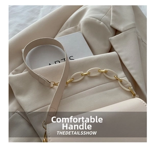 Detail of cream leather handbag with decorative acrylic and gold metal chain link