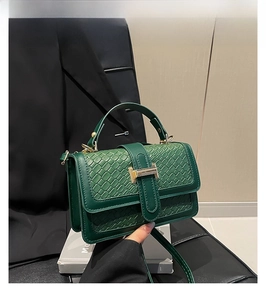Detail view of woven leather green crossbody bag with gold H-clasp and side gusset