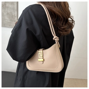 Dettaglio borsa a spalla beige con fibbia dorata geometrica e tracolla con nodo sottile