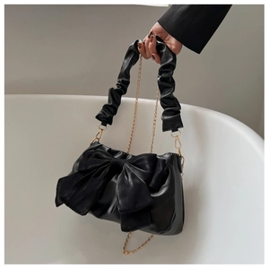 Black fashion handbag with a large bow detail, ruched handle, and gold chain strap