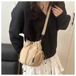 Detail of khaki drawstring bucket bag showing mesh side pocket and fashion label on nylon