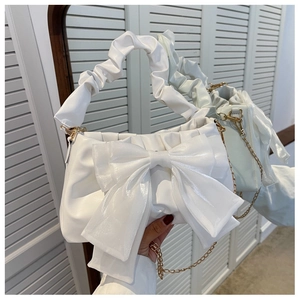 Detail of white handbag with large pearl-gloss bow and ruched scrunchie handle strap