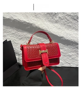 Detail of red woven texture handbag with gold metal accents and adjustable strap
