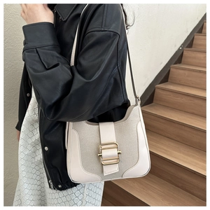 Close-up of vintage contrasting shoulder bag with gold buckle and stitched leather detail