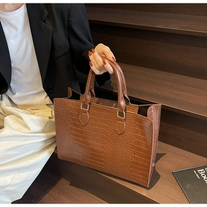 Close-up of brown crocodile pattern tote bag with golden hardware and twin handles