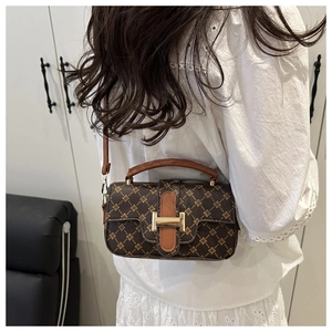 Rear view of model wearing a vintage patterned brown crossbody bag with gold metal clasp