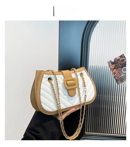 Détail du sac à chaîne matelassé kaki et blanc avec boucle géante porté par un mannequin