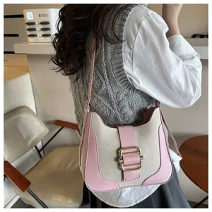 Detail of pink and beige canvas saddle bag showing golden buckle on a shoulder strap