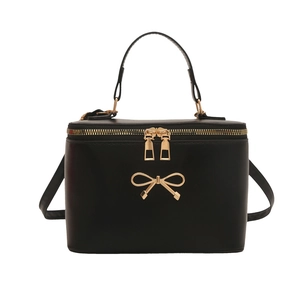 Retro black box handbag with golden bow detail and top handle on a white background