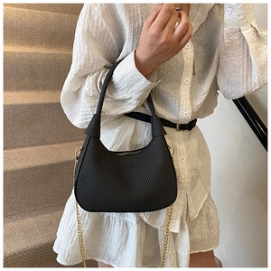Close-up of black woven texture hobo bag with elegant gold chain and top handle detail