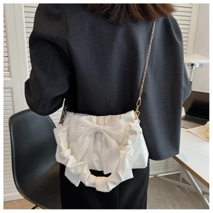 Fashionable white glossy shoulder bag with large bow decoration and gold chain strap