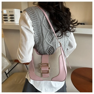 Detail of pink leather and beige canvas crossbody bag with metal buckle on model