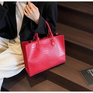 Detailed view of red crocodile embossed pattern on a large capacity fashion tote bag