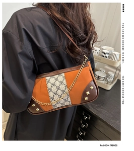 Model wearing a retro two-tone shoulder bag with orange canvas and gold chain strap