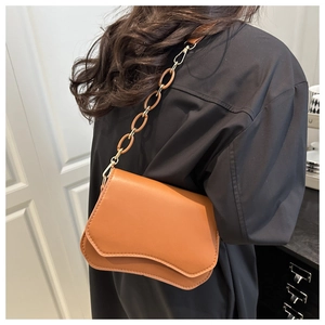 Brown faux leather flap bag with wave-edge design and chunky chain strap on shoulder