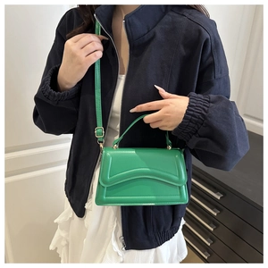Sac à main en cuir vert texturé avec motif géométrique porté par un mannequin