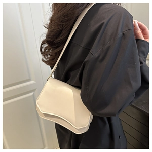Detail of off-white crossbody bag with geometric flap and metal clasp on black shirt