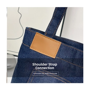 Detailed close-up of heavy-duty reinforced orange stitching on dark blue denim tote strap