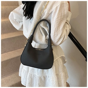 Detail of black woven crescent bag with golden chain strap on a model shoulder