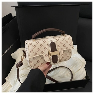Detailed view of cream and brown clover print bag with gold metal lock on gift packaging