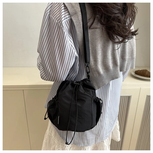 Detail view of black drawstring bucket bag with mesh pocket and white fashion label on fabric