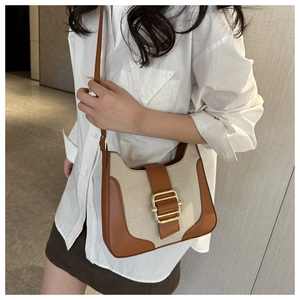 Detail of vintage crossbody bag with brown leather, beige canvas, and golden buckle