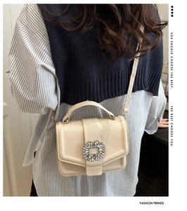 Detail of beige leather crossbody bag featuring a sparkling crystal circular buckle